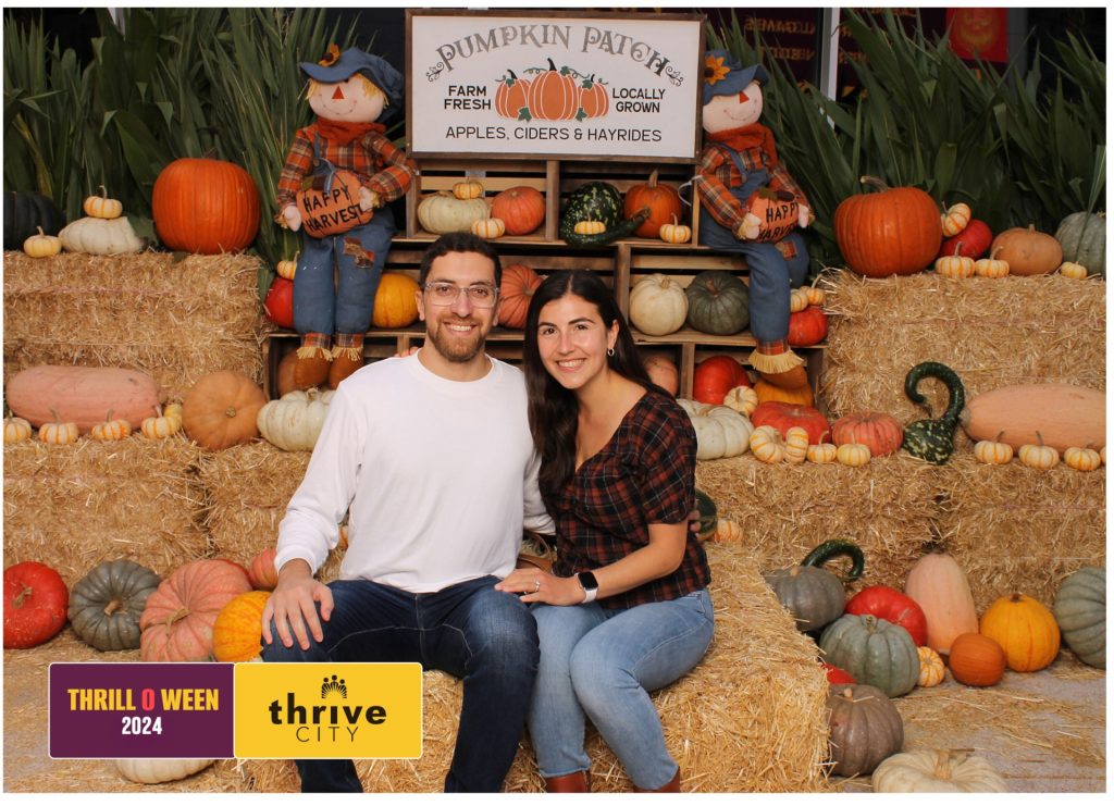 Man and woman taking a photo in front of a Halloween Photo Booth.