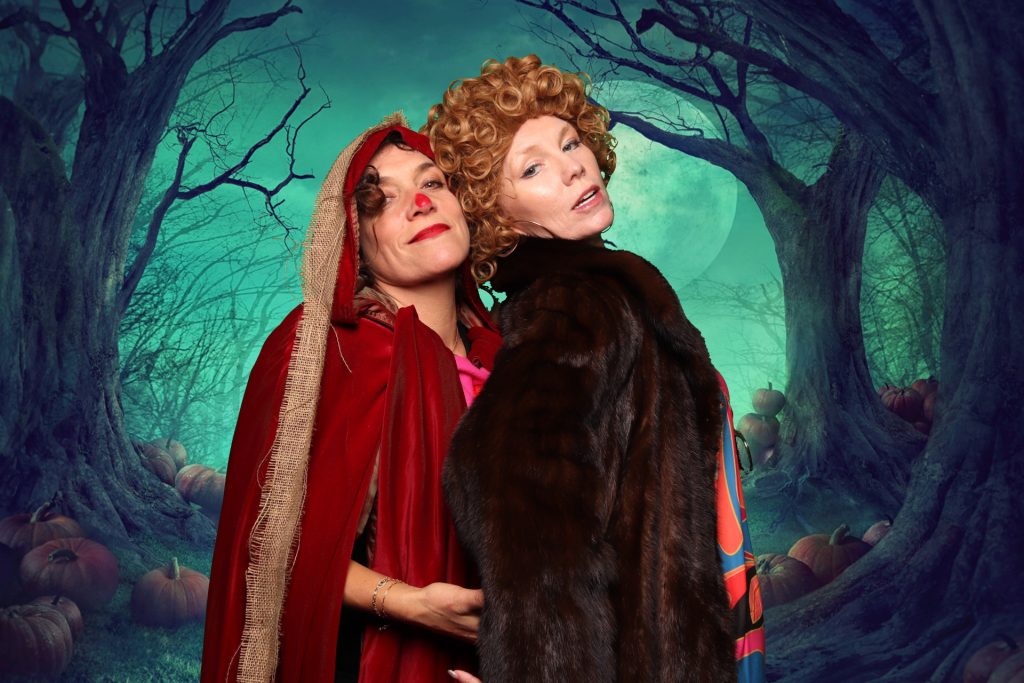 Two women dressed in costume taking a photo in front of a greenscreen Halloween Photo Booth.