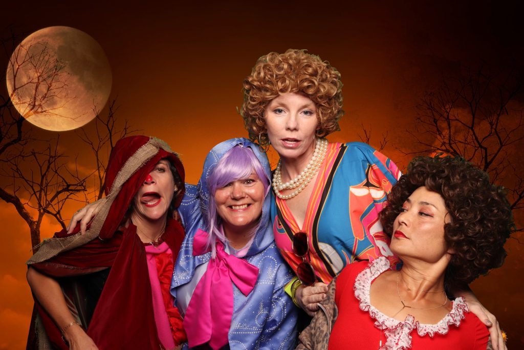 Group of women dressed in costume taking a photo in front of a greenscreen Halloween Photo Booth.
