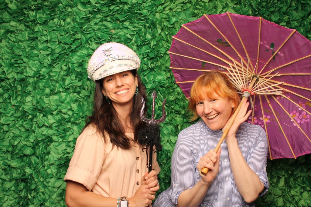 Two women pose for a photo in front of a spring open-air photo booth.