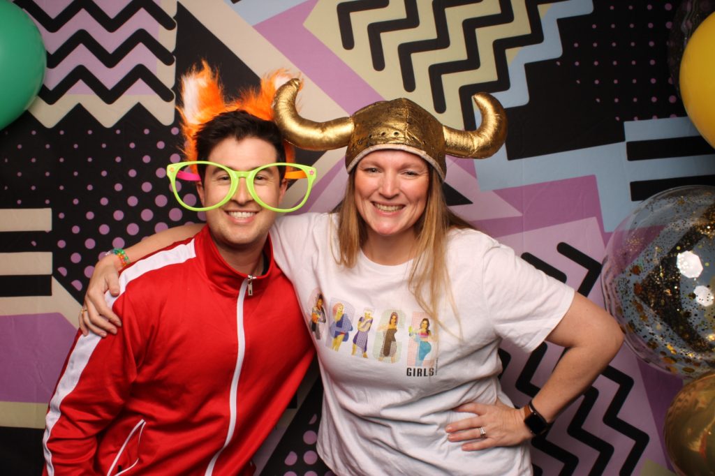 Man and Woman pose for a photo in front of an open-air photo booth.