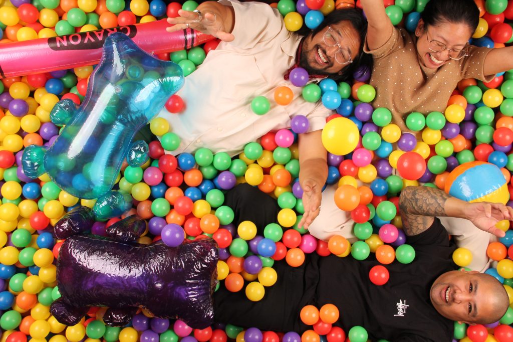 Group pose for a photo in a ball pit photo booth.