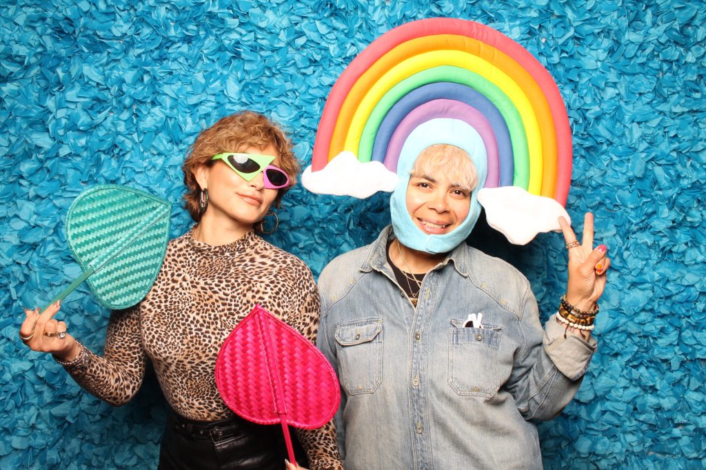 Man and woman pose for a photo in front of an open-air photo booth.