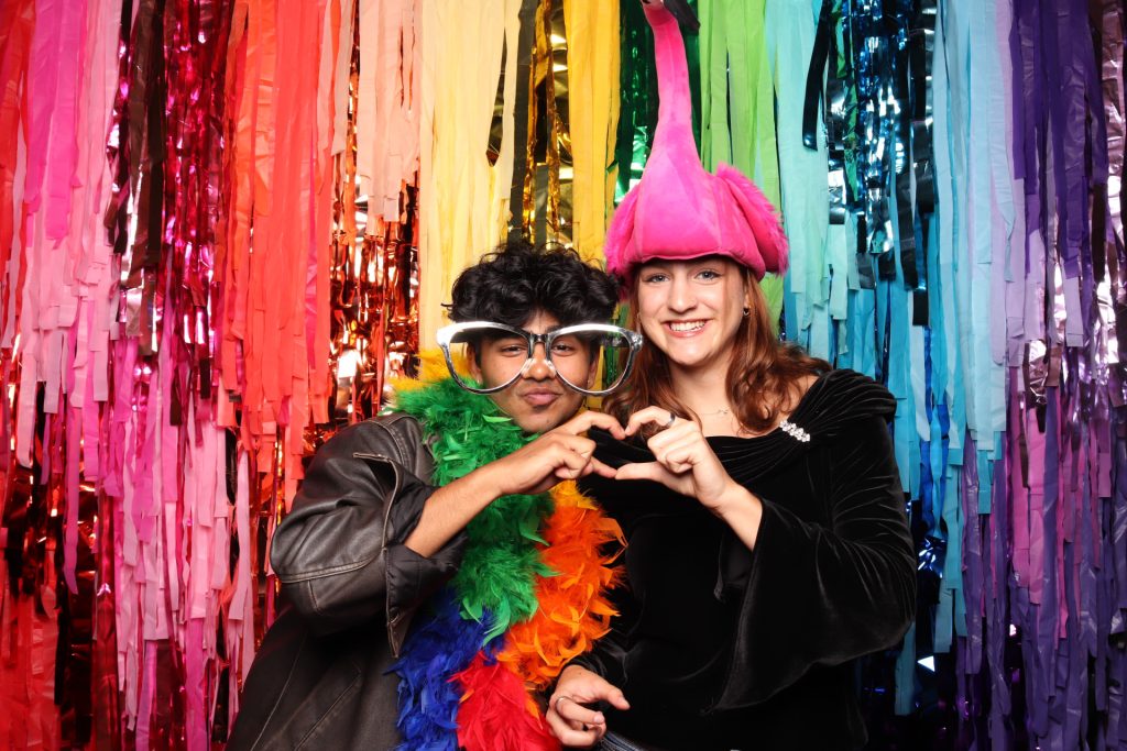 Man and woman pose for a photo in front of a colorful backdrop.