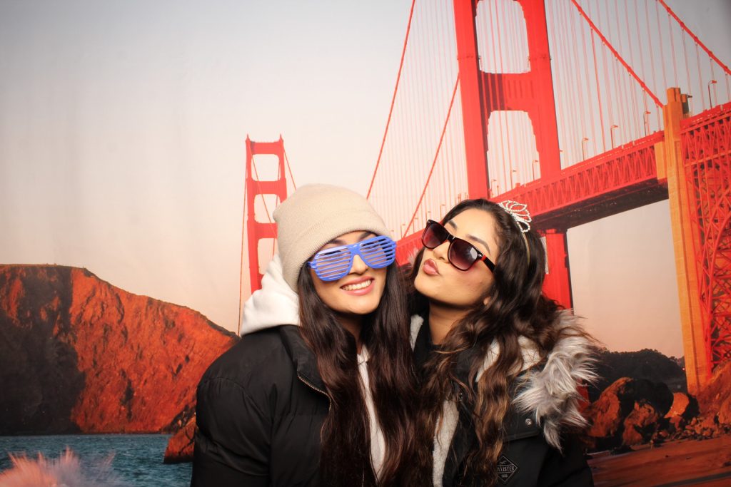 Two girls pose for a photo in front of a San Francisco Photo Booth