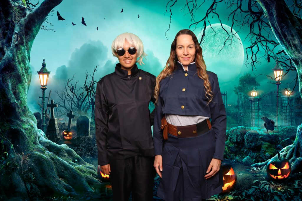 Two women dressed in costume taking a photo in front of a greenscreen Halloween Photo Booth.