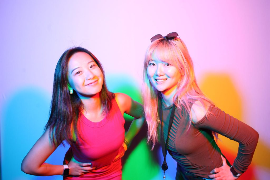 Two girls posing for a photo in front of the RGB Colored Shadow Set for a spring photo booth.