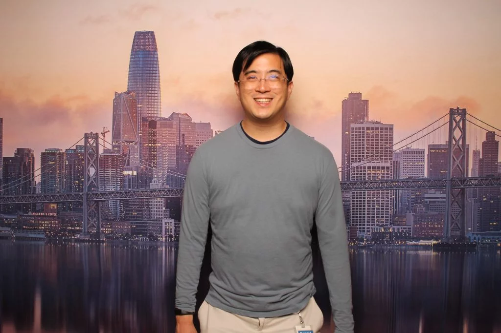 Guy stands for a photo in front of the San Francisco Sunset backdrop