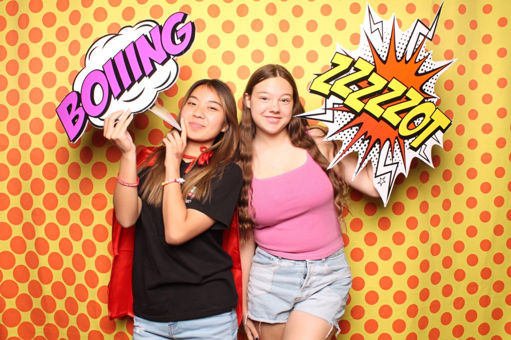 Two women posing for a photo in the Open-Air photo booth.