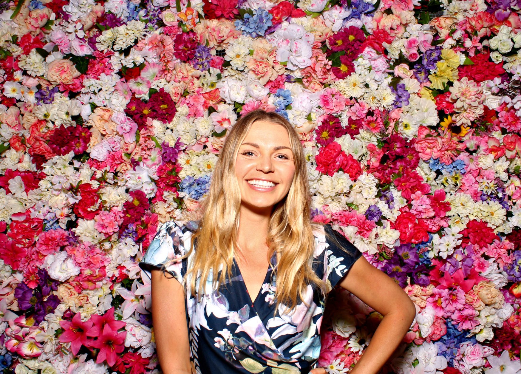 Woman poses for a photo in front of the Floral Wall set.