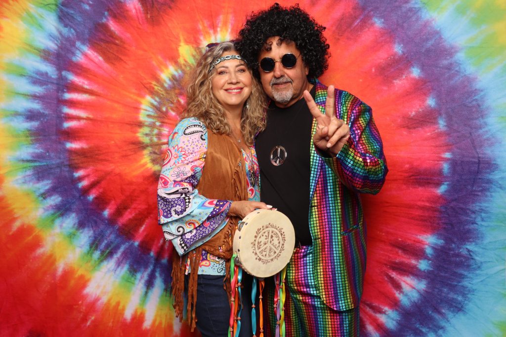 Couple poses for a photo in front of Tie-dye backdrop.