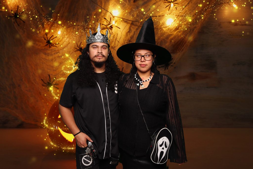 Man and woman dressed in costume taking a photo in front of a greenscreen Halloween Photo Booth.