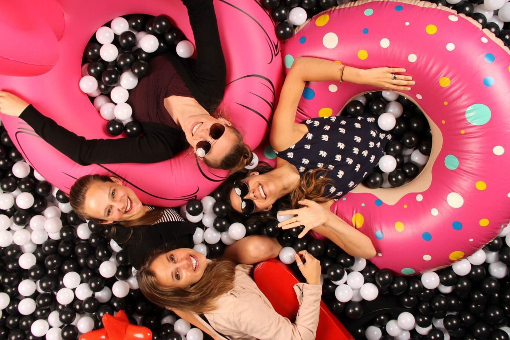 a group of women with innertubes in a black and white ballpit photobooth