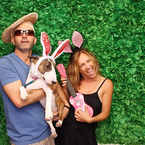 a woman and a man holding in a photobooth with a green background