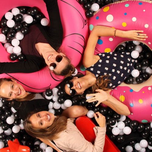 a group of women with innertubes in a black and white ballpit photobooth