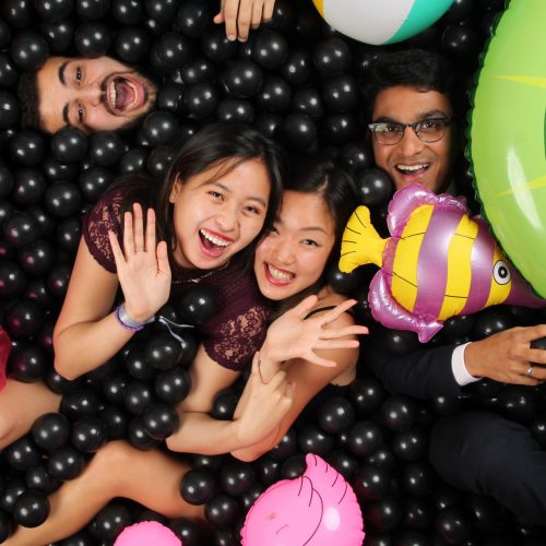 a group of people in a black ballpit photobooth with inflatable toys