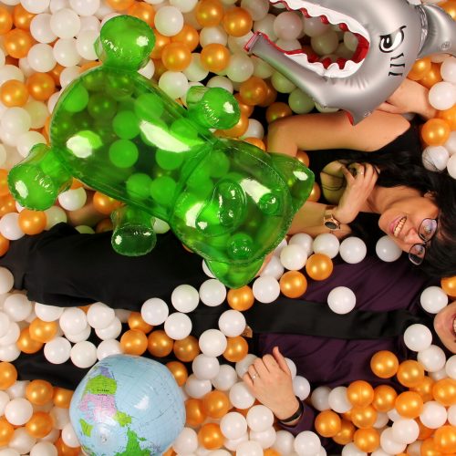 a woman and a man posing with inflatable toys in an orange and white ballpit
