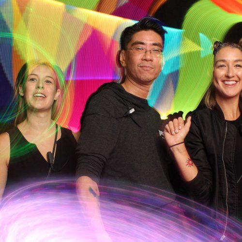 three people in front of colorful light paintings