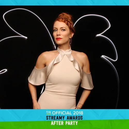 woman posing with a white light painting behind her that looks like wings