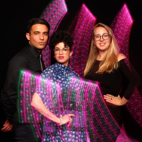 three people posing with pink light paintings behind and in front of them