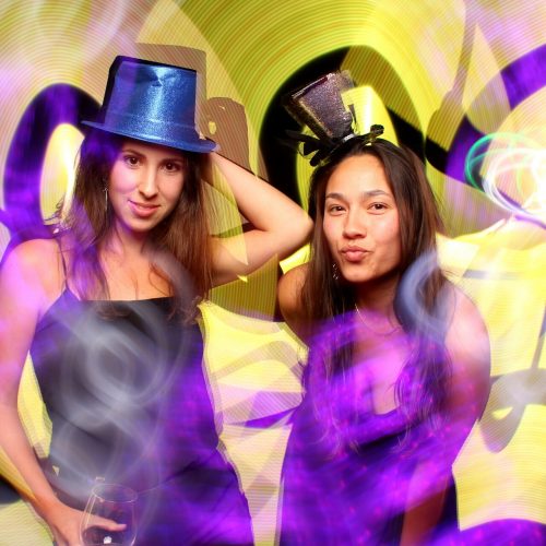 two women wearing hats in a light painting photo booth