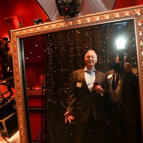 a man and a photographer smiling in a mirror photo booth