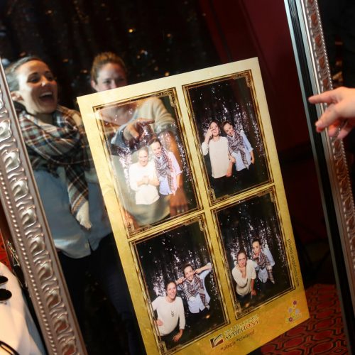 two women smiling at the photos they took in a mirror photo booth