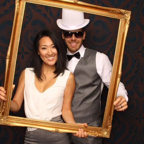 a man and a woman holding up a frame in a photobooth