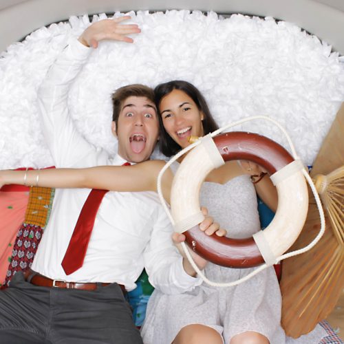 two people posing in a vehicle photo booth with an inner tube