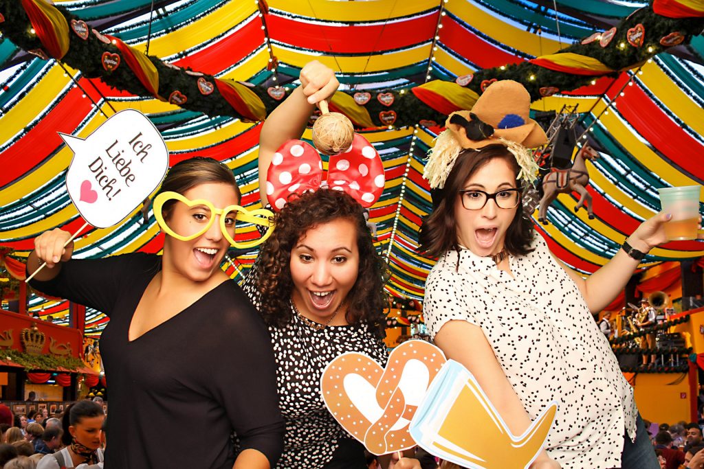 three women posing with silly props in front of a custom background