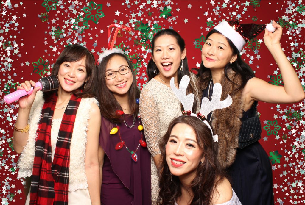 Group of women posing for a holiday photo in front of a greenscreen photo booth.
