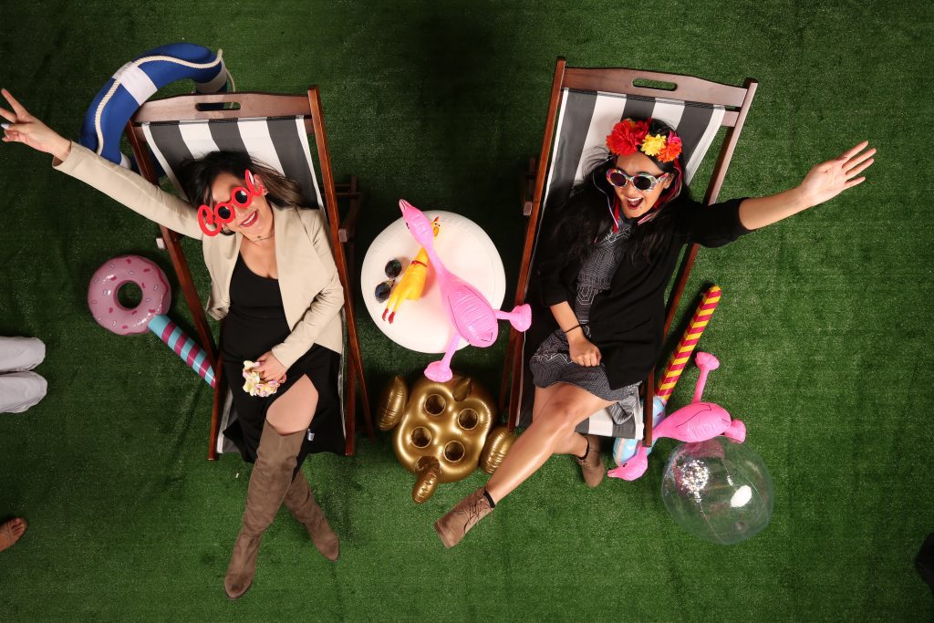 two women sitting in beach chairs posing with inflatables